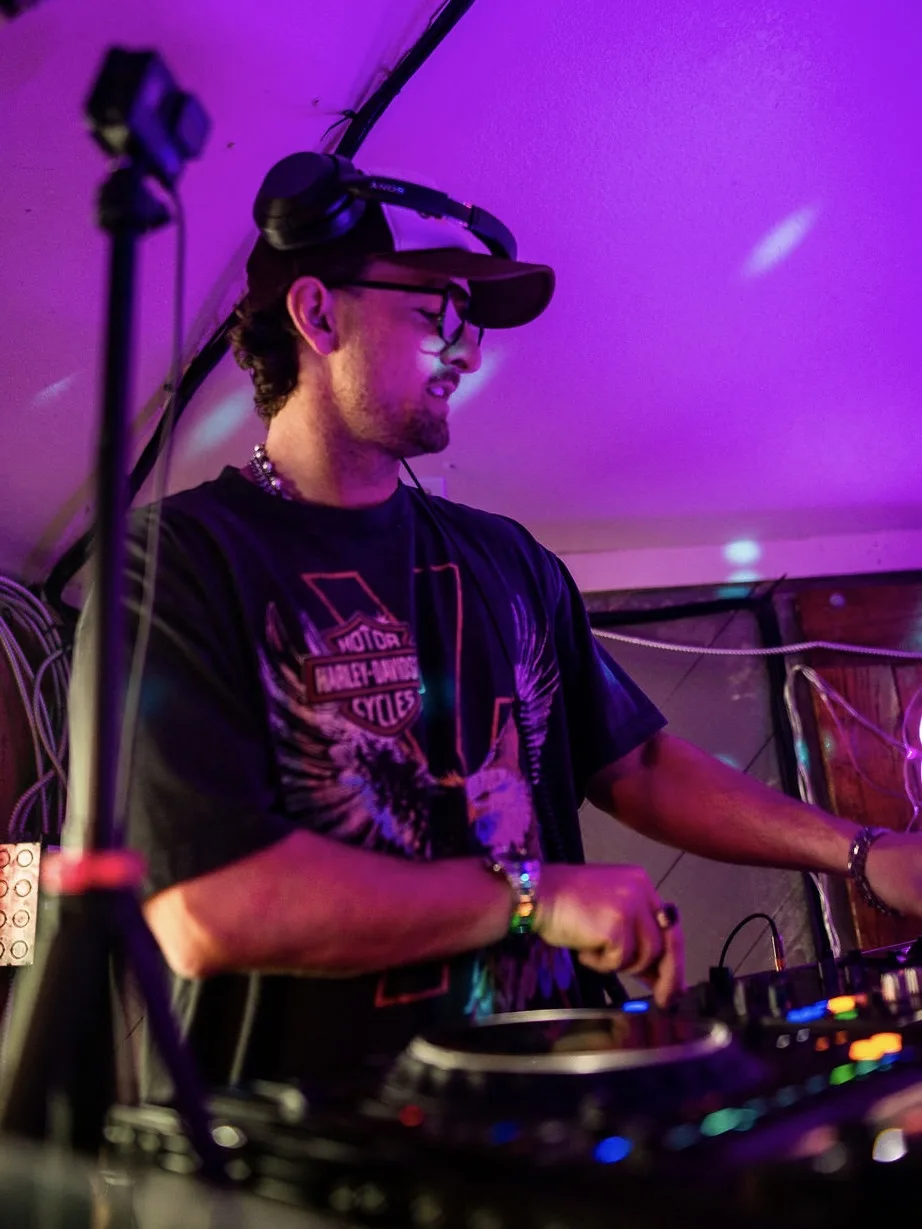 AUSTAL DJing under purple stage lighting, headphones around his cap